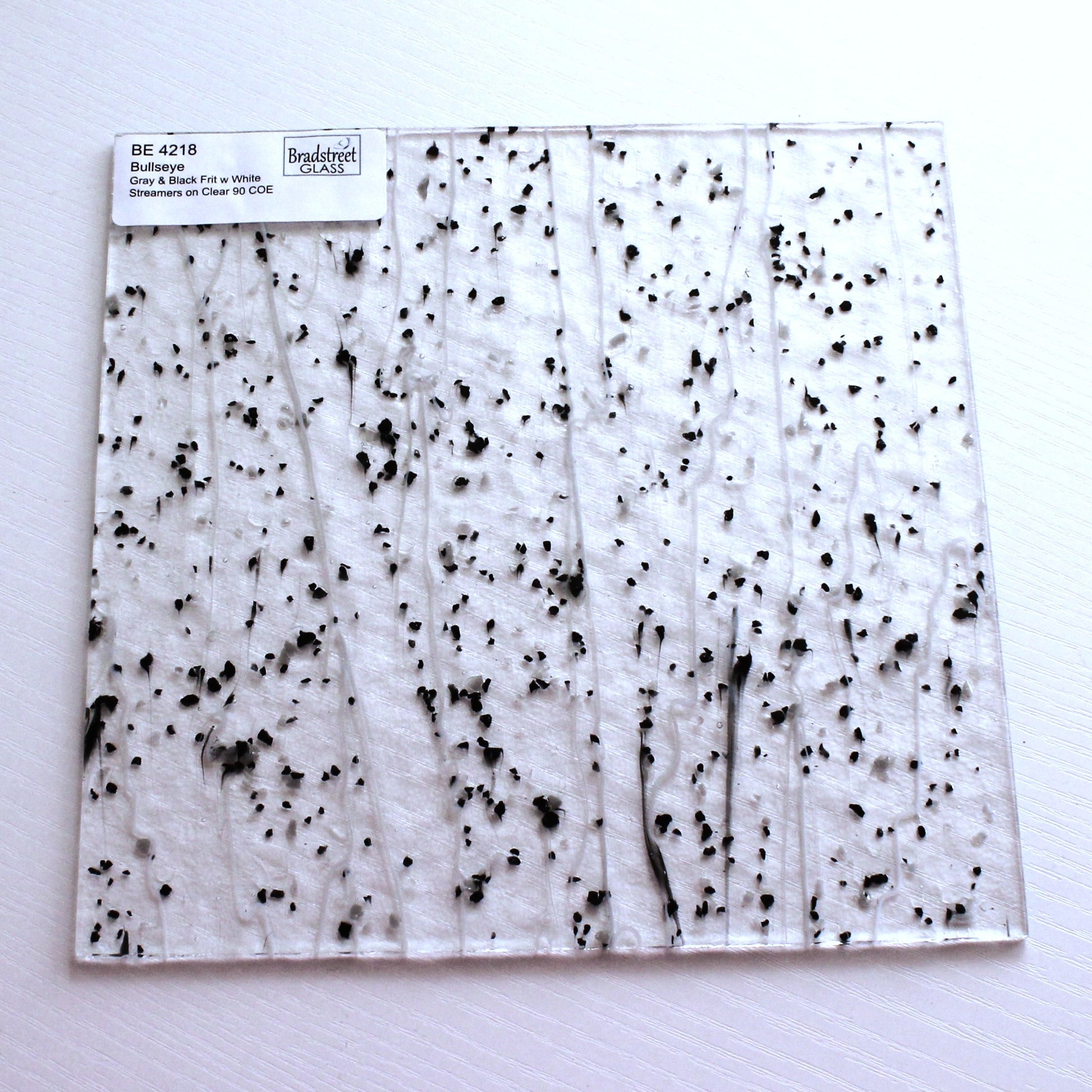 Gray & Black Frit, White Streamers on Clear Stained Glass Sheet. Bullseye 4218 Fusible 90 COE Fusible stringer glass, fusible frit glass.  Bradstreet Glass