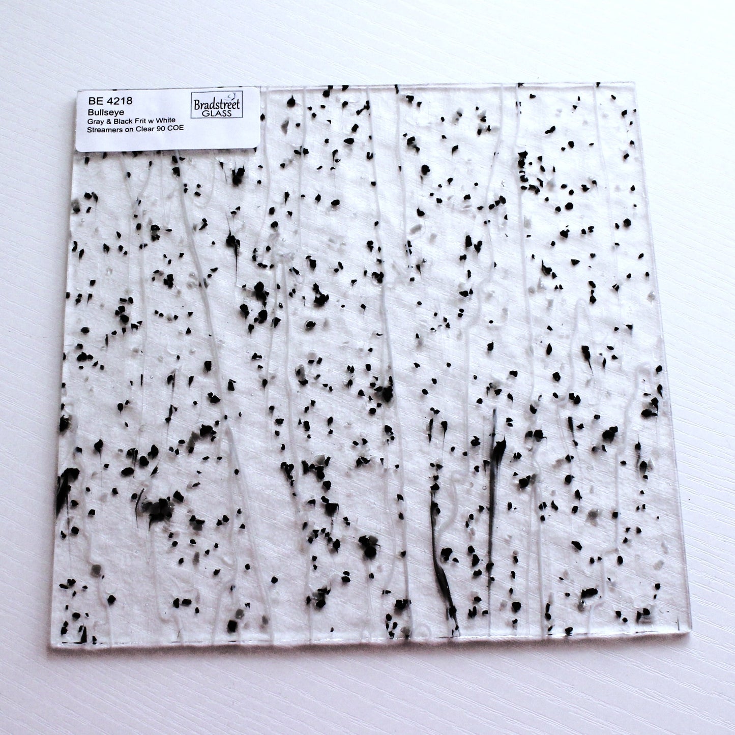 Gray & Black Frit, White Streamers on Clear Stained Glass Sheet. Bullseye 4218 Fusible 90 COE Fusible stringer glass, fusible frit glass.  Bradstreet Glass