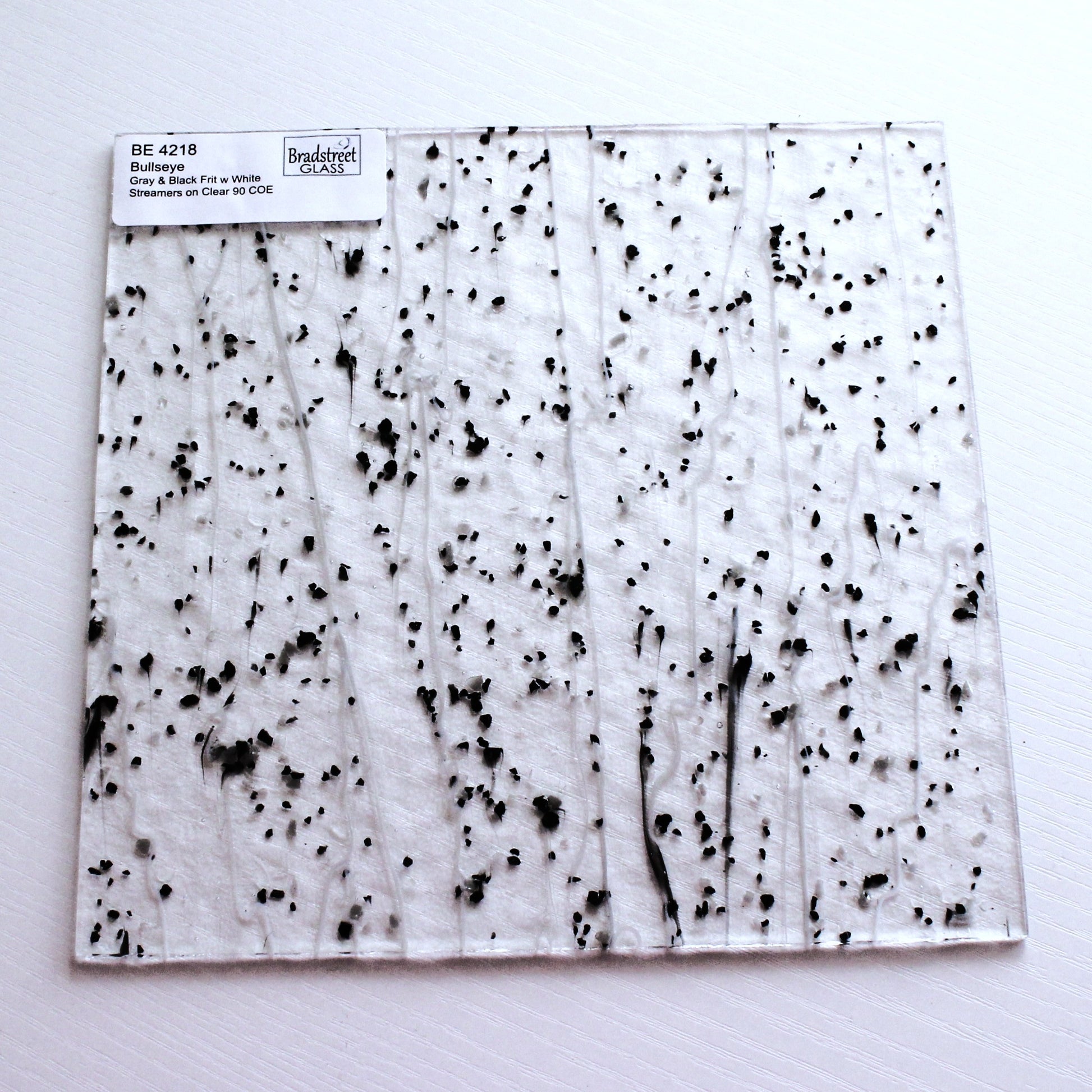 Gray & Black Frit, White Streamers on Clear Stained Glass Sheet. Bullseye 4218 Fusible 90 COE Fusible stringer glass, fusible frit glass.  Bradstreet Glass