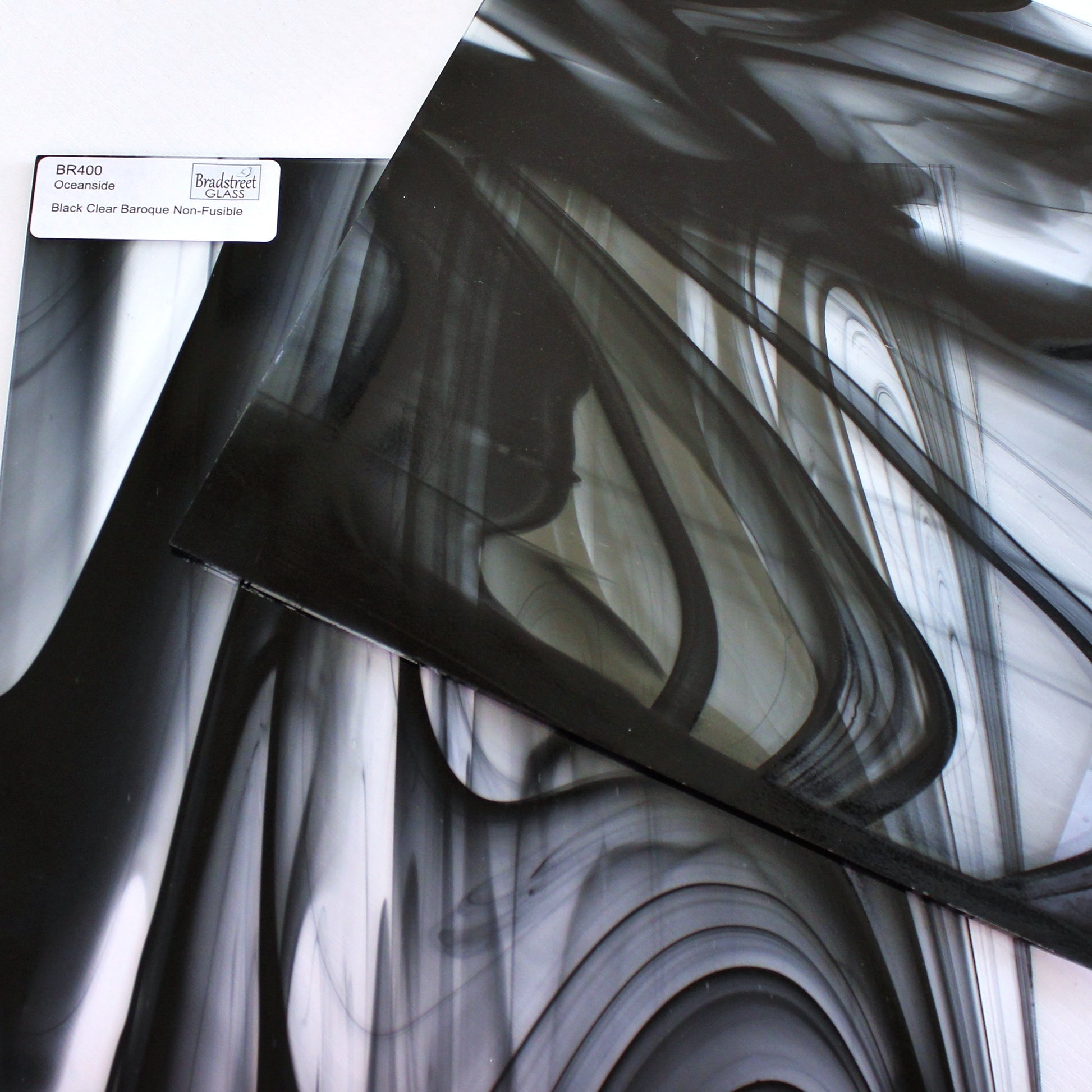 Close-up Oceanside BR400 black and clear baroque stained glass sheet showing bold irregular mixture with high-contrast pattern. Bradstreet Glass