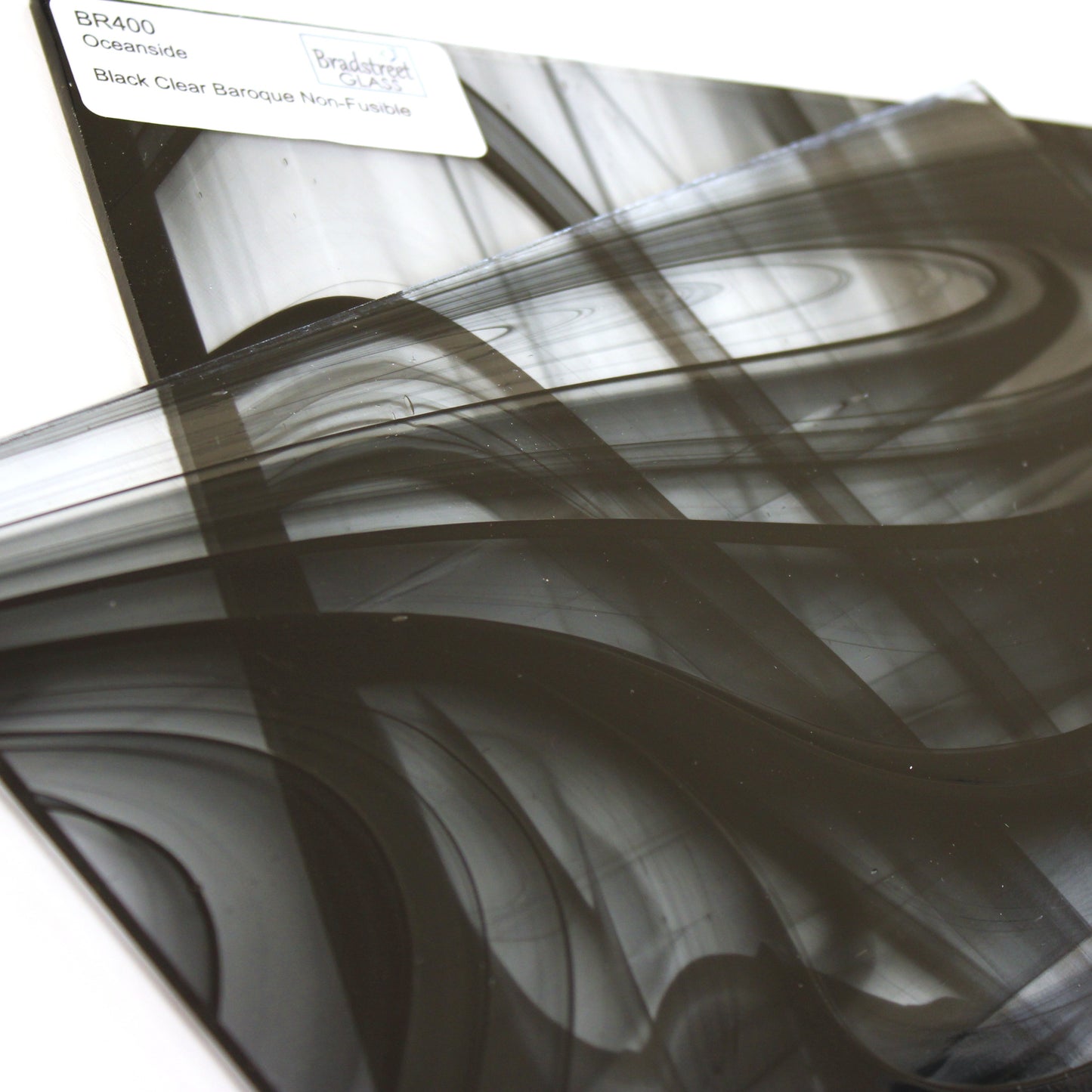 Close-up Oceanside BR400 black and clear baroque stained glass sheet showing bold irregular mixture with high-contrast pattern. Bradstreet Glass