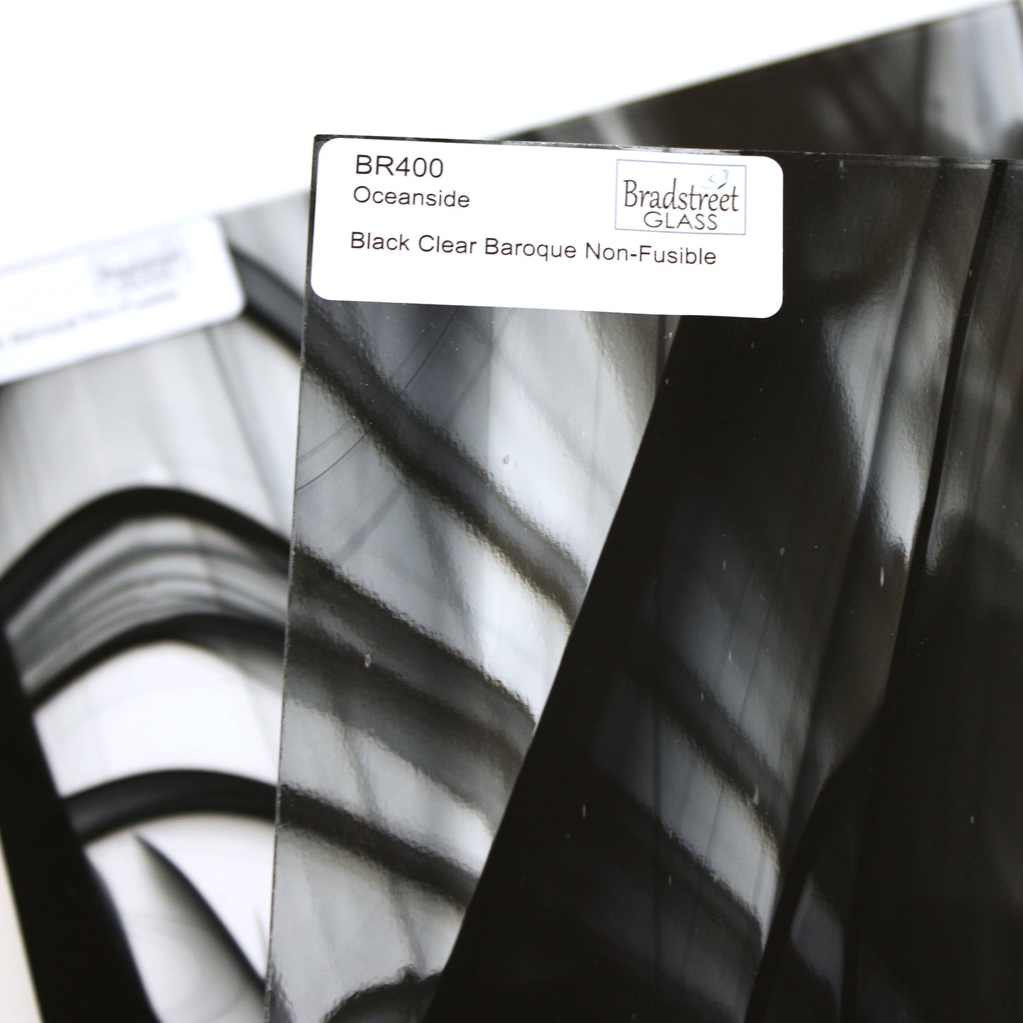 Close-up Oceanside BR400 black and clear baroque stained glass sheet showing bold irregular mixture with high-contrast pattern. Bradstreet Glass