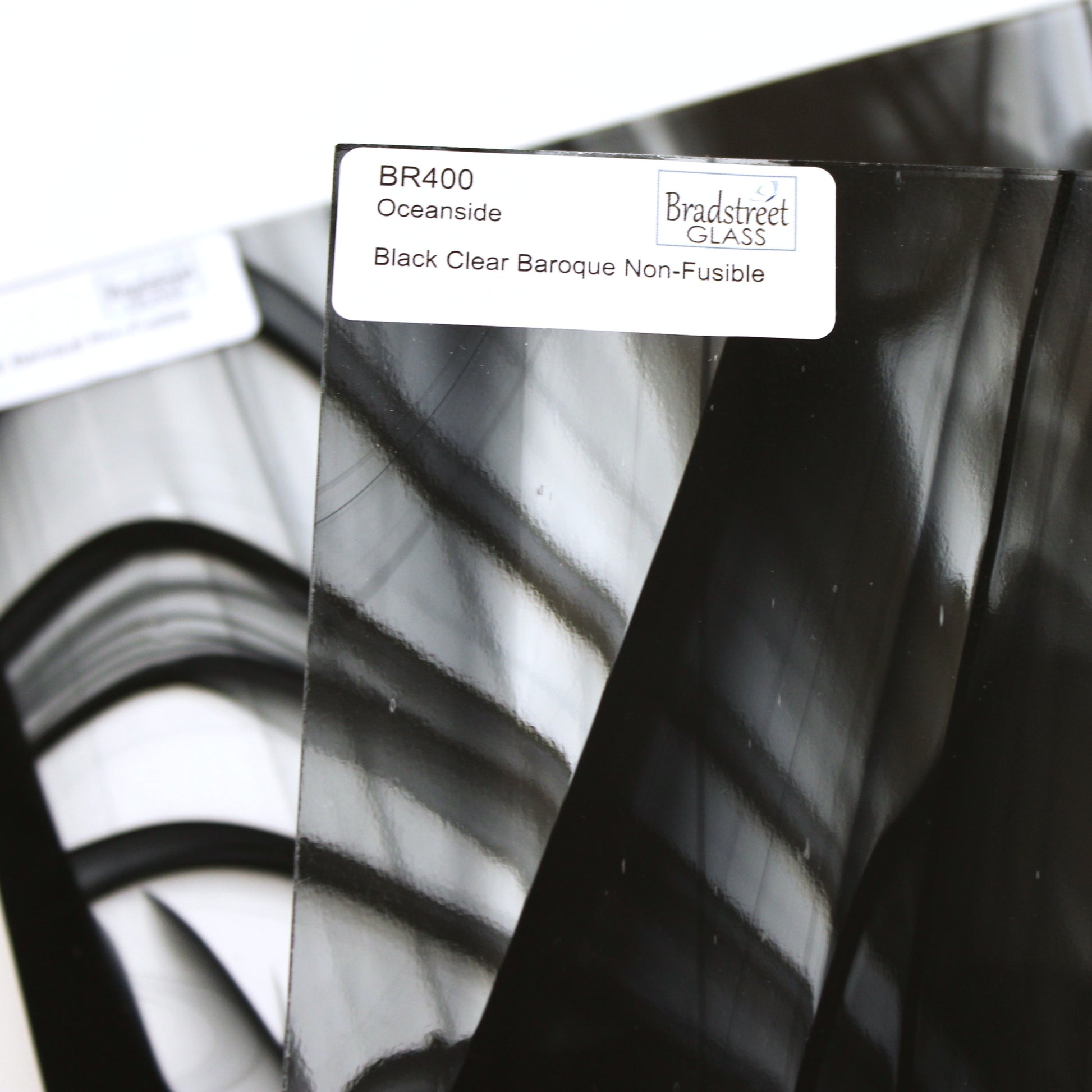 Close-up Oceanside BR400 black and clear baroque stained glass sheet showing bold irregular mixture with high-contrast pattern. Bradstreet Glass