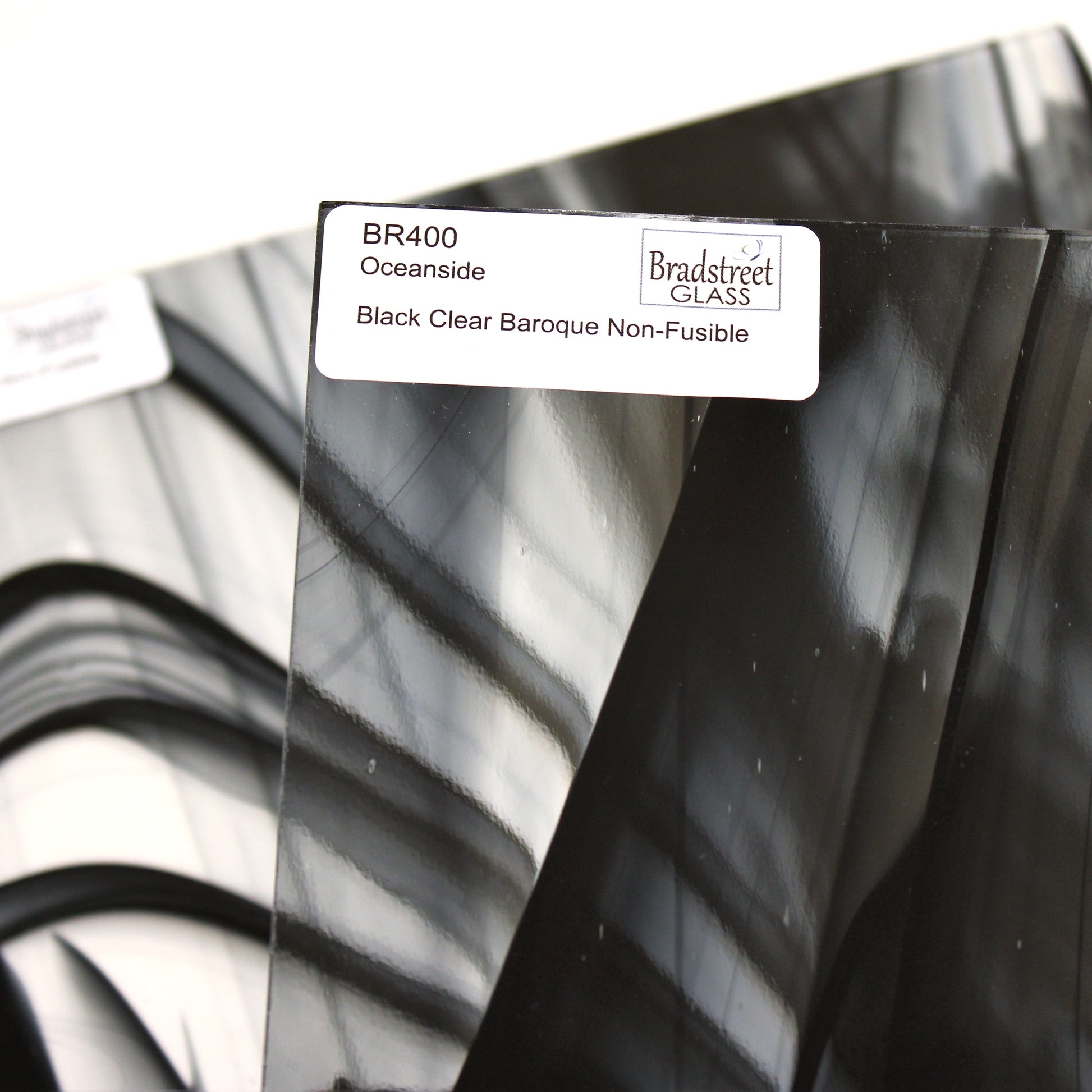 Close-up Oceanside BR400 black and clear baroque stained glass sheet showing bold irregular mixture with high-contrast pattern. Bradstreet Glass