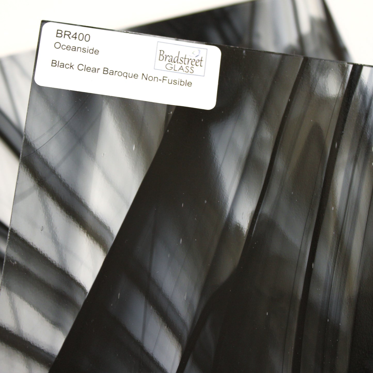 Close-up Oceanside BR400 black and clear baroque stained glass sheet showing bold irregular mixture with high-contrast pattern. Bradstreet Glass
