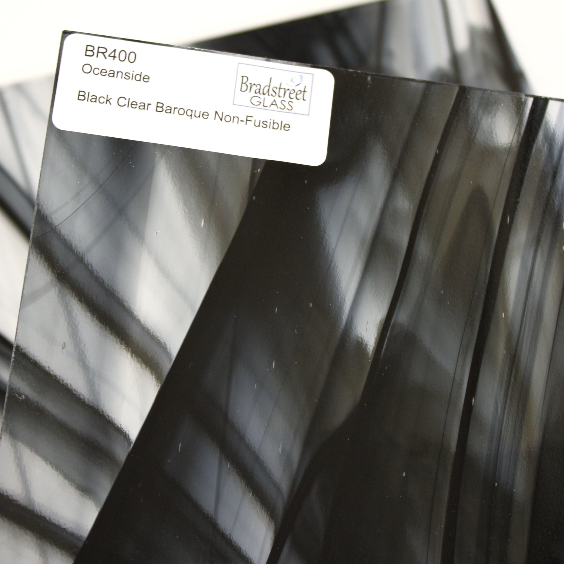 Close-up Oceanside BR400 black and clear baroque stained glass sheet showing bold irregular mixture with high-contrast pattern. Bradstreet Glass